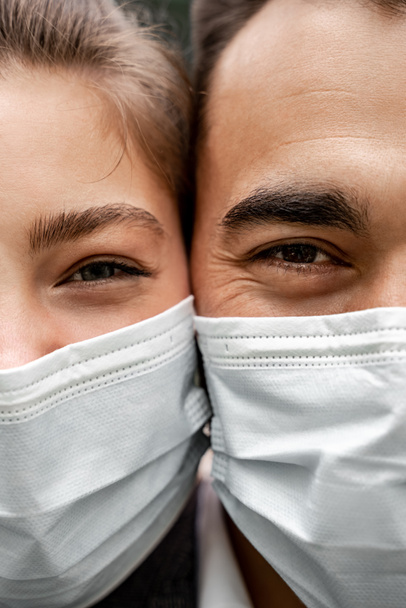 обрезанный вид молодых мужчин и женщин в медицинских масках, смотрящих в камеру - Фото, изображение