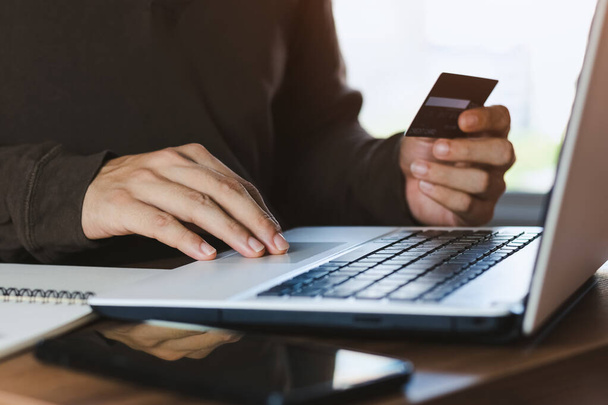Businessman hand holding credit card with using laptop for online shopping while making orders at home. business, lifestyle, technology, ecommerce, digital banking and online payment concept. - Photo, Image