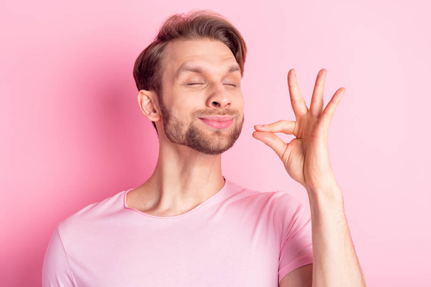 Foto von beeindruckt lustige junge Herr gekleidet lässig T-Shirt lächelnd versuchen leckeres Essen isoliert rosa Farbe Hintergrund - Foto, Bild