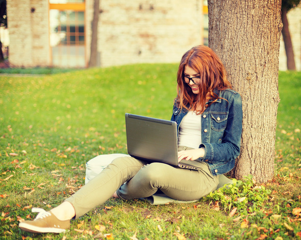 smiling teenager in eyeglasses with laptop - Photo, Image