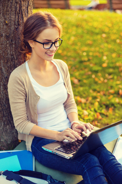 smiling teenager in eyeglasses with laptop - Foto, Bild