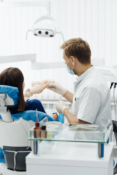 Стоматолог проверяет и выбирает цвет молоденьких женских зубов - Фото, изображение
