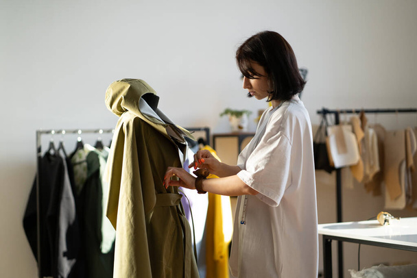 Молодой портной настроить воротник детали модели одежды на манекен с иглами в студии моды - Фото, изображение