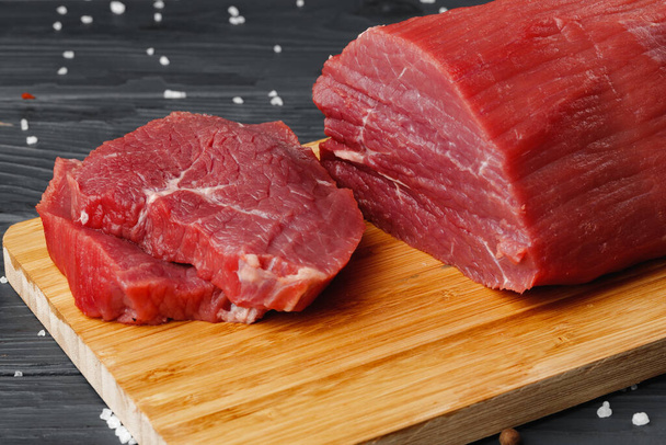 Beef tenderloin on wooden board on wooden table - Photo, image