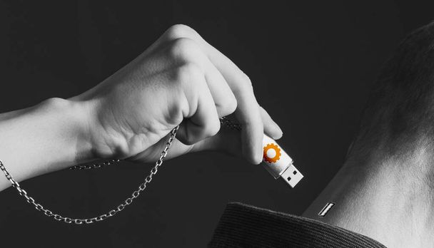 Collage, a man's hand holding a flash drive on a chain inserts it into another person's head - Photo, Image