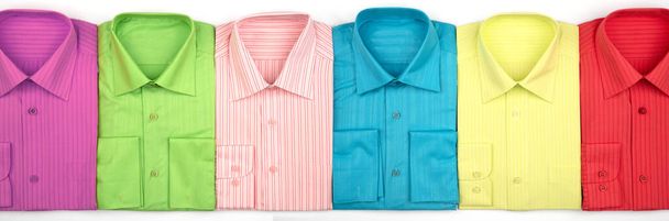 Egy új ing egy bolt vagy raktár ablakában. Uniszex sokszínű ruhák. Értékesítés, kedvezmények, előléptetés koncepció. Piros, zöld, rózsaszín, sárga színek - Fotó, kép