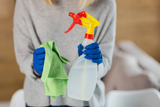hands of female cleaning lady holding rag and antiseptic and detergent in hands photo from close up - Photo, image