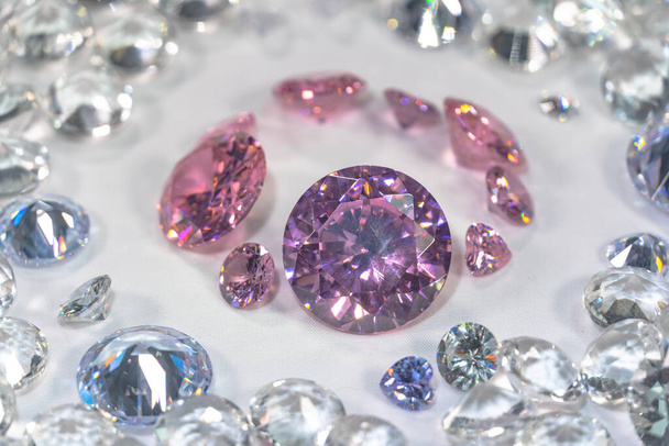 Een groep roze diamanten gerangschikt in het midden van witte diamanten in een witte achtergrond - Foto, afbeelding