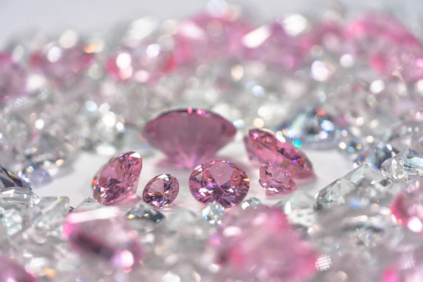 Группа розовых бриллиантов, расположенных посреди белых бриллиантов на белом фоне - Фото, изображение