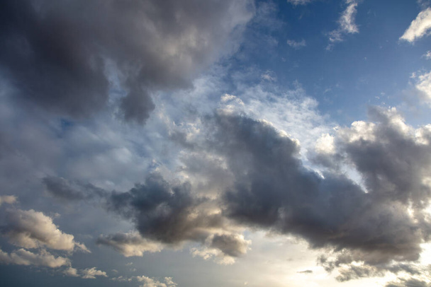 Bedecktes Konzept. Schwere dunkle Regenwolken auf blauem Himmel im Hintergrund. Wolkenlandschaft farbenfroher Horizont, abstrakt, Sonnenstrahlen, die den Himmel färben machen es idyllisch. - Foto, Bild