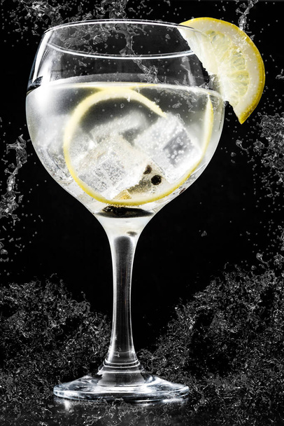 Gin tonic cocktail splash on black background - 写真・画像