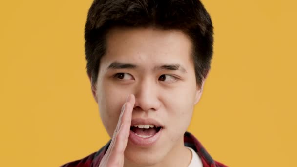 Asiatique Guy chuchotant partager ses secrets sur fond jaune - Séquence, vidéo