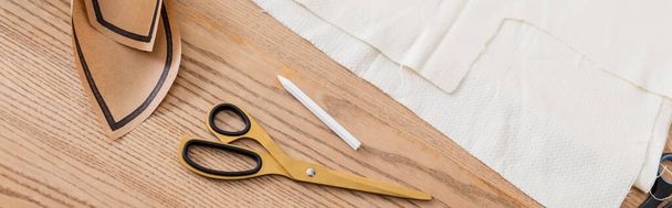 High angle view of cloth, scissors and sewing pattern on table, banner  - 写真・画像