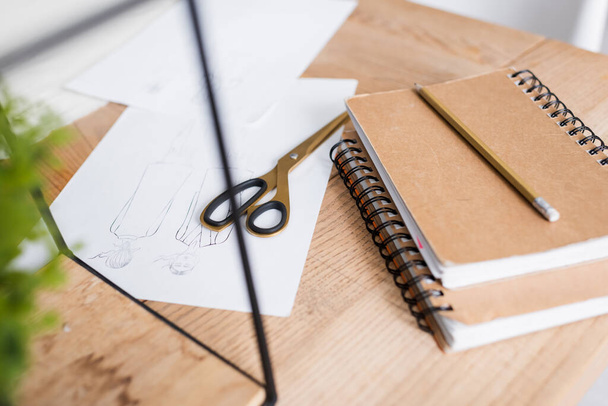 Sketches near scissors and notebooks on table  - Φωτογραφία, εικόνα