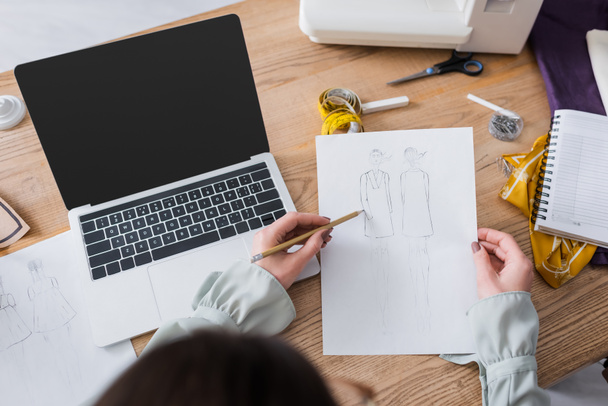 Overhead view of designer drawing sketches near laptop and sewing machine  - Fotoğraf, Görsel