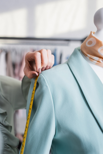 Cropped view of young seamstress with tape measure measuring jacket  - Photo, Image
