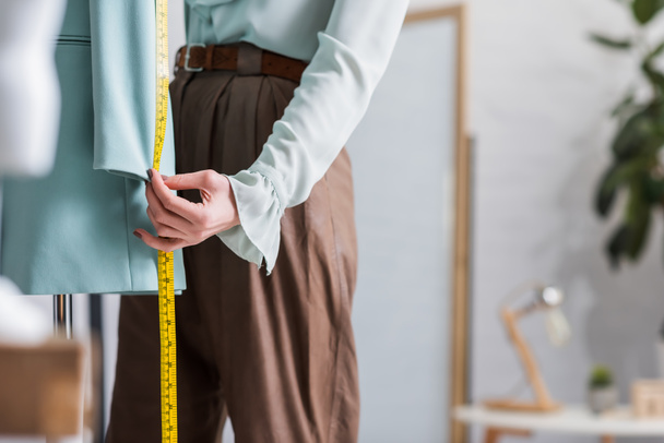 Cropped view of seamstress with tape measure near blurred blazer  - Photo, Image