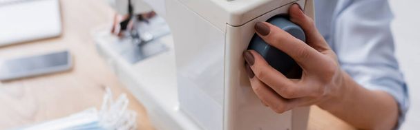 Обрізаний вид швайна регулювання швейної машини біля розмитих медичних масок, банер
  - Фото, зображення