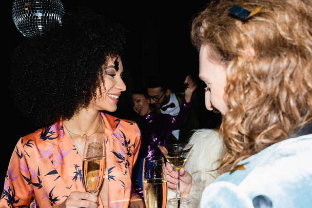 glücklich multirassische Freunde trinken in Nachtclub auf schwarzem Hintergrund - Foto, Bild