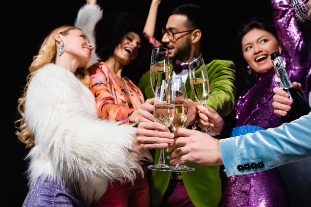 счастливые межрасовые друзья звонят с бокалами шампанского на черном фоне - Фото, изображение