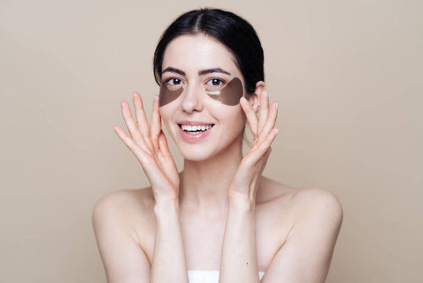 Young beautiful woman with clean fresh facial skin, uses eye patches - Foto, afbeelding