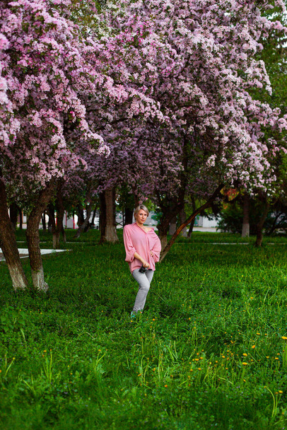 Kaunis nuori nainen kirsikankukkien puutarhassa - Valokuva, kuva