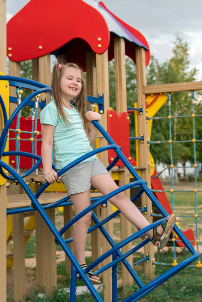 Liebenswert lächelndes kleines Mädchen mit zwei lustigen Schwänzen, die Spaß auf dem Spielplatz haben. - Foto, Bild