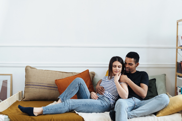 Vista frontale di giovani coppie diverse sedute su un divano a casa - Foto, immagini