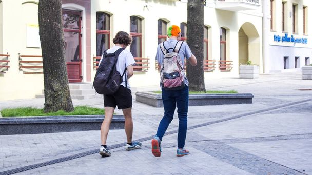 Guys are walking along Komsomolskaya Street in Minsk on July 14, 2018. One guy has his hair dyed orange and green. Hippie - Photo, Image