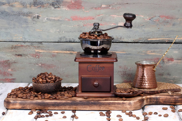 素朴な背景を持つテーブルの上にコーヒー豆とグラインダー - 写真・画像