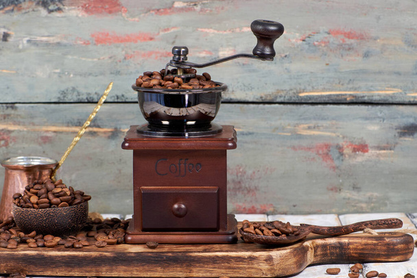 Koffiebonen en molen op tafel met rustieke achtergrond - Foto, afbeelding