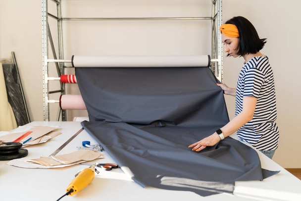 Jóvenes sastres llevan rollo de tela a patrón cur medida textil trabajando en la nueva colección en taller - Foto, imagen