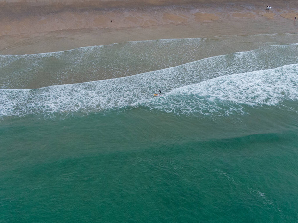 Surfers and paddle boarders from a above aerial drone holywell bay cornwall england uk - Фото, изображение