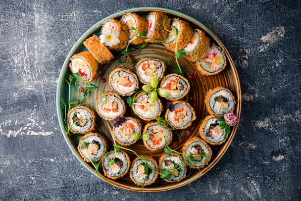 set hot sushi rolls fried in a round tray. Assortment of delicious tempura and baked sushi maki with salmon, eel, cucumber, avocado, scrambled eggs, shrimp. Japanese oriental cuisine - Foto, afbeelding