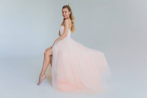 Middle age blond lady in pink dress posing on gray background. - Foto, immagini