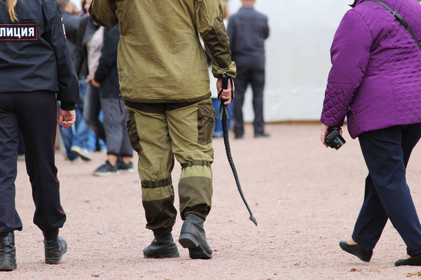 Wachmann eines privaten Sicherheitsdienstes patrouilliert während eines Nationalfeiertags mit Leuten, die eine Peitsche in der Hand halten. - Foto, Bild