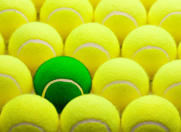 Skupina žlutých tenisových míčků a jedna zelená. - Fotografie, Obrázek