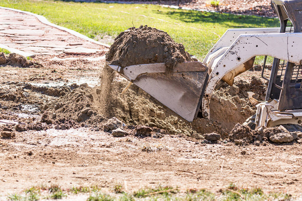 Pequeña excavadora de toros en el patio para la instalación de la piscina. - Foto, imagen
