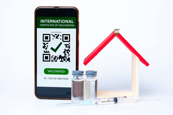 Uma foto de smartphone com falso Certificado Internacional de Vacinação nele. Também vacina Covid-19 e visão em miniatura da casa. A vacinação domiciliar é pobre em muitos países. - Foto, Imagem