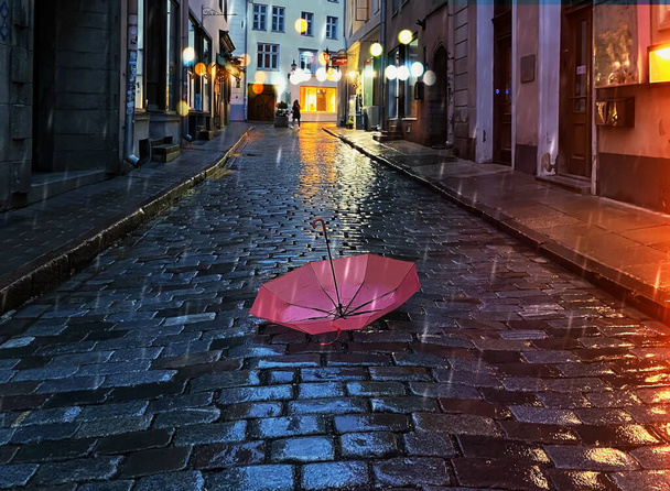 pink umbrella on wet pavement at rainy medieval evening street light plurred reflektion rain fall  in Tallinn old town Estonia  - Photo, Image