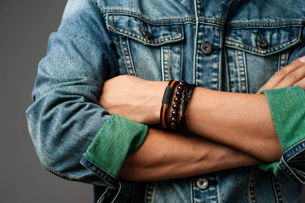 The man in jean jacket wearing bracelets, casual style of men accessories. Shallow depth of field. - Photo, image