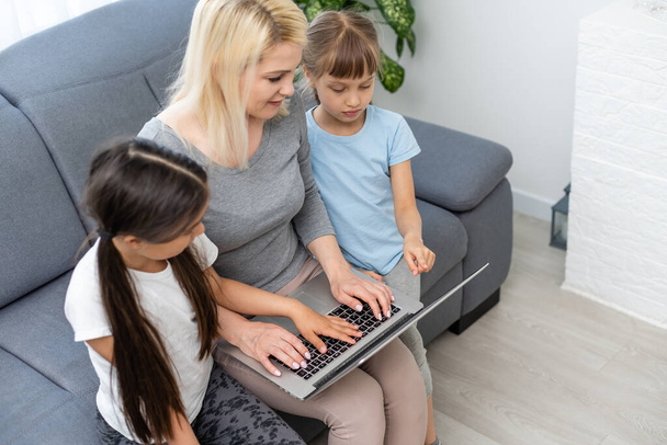 Working from home office with kid. Happy mother and daughter shopping online, using laptop together. Woman hugging child. Freelancer workplace at kitchen table. Female business, virtual communication. - Photo, Image