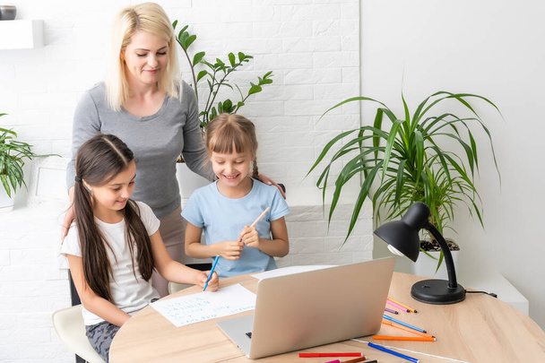 Homeschool młodych dwóch córek uczących się Internetu w Internecie odrabiać lekcje za pomocą komputera z pomocą matki, uczyć i zachęcać. Dziewczyna i młodsza siostra chętnie uczyć się w domu razem - Zdjęcie, obraz