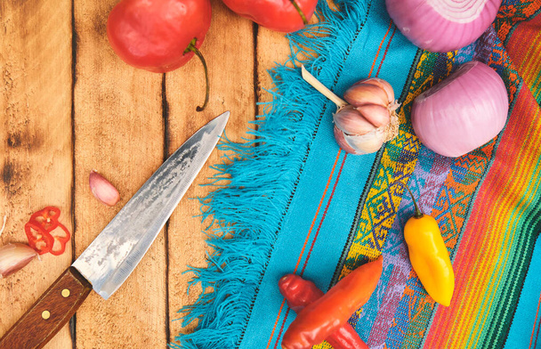 Ingredientes peruanos: Verduras con tabla de cortar, chile Rocoto que ha sido rebanado en una tabla de madera, chile Aji Limo, ajo y cebolla - Foto, Imagen