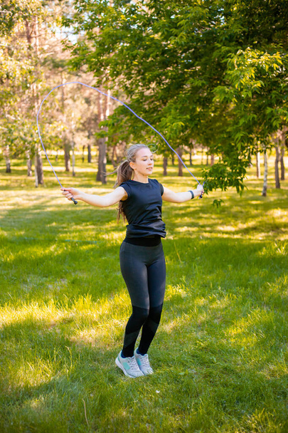 Młoda kobieta skacząca po trawniku w letnim parku. Modelka skoku. Koncepcja zdrowego trybu życia i sportu na świeżym powietrzu. - Zdjęcie, obraz