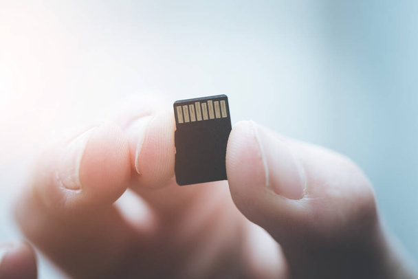 Young man is holding a tiny memory card in his hand, text space - Photo, image