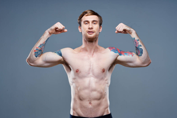 vahva mies urheilija pumpataan ylös käsivarren lihaksia ja tatuointi kehonrakentaja kunto - Valokuva, kuva