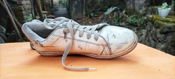 μια φωτογραφία ξεχασμένων, φθαρμένων παπουτσιών, βρώμικων και σκονισμένων - Φωτογραφία, εικόνα