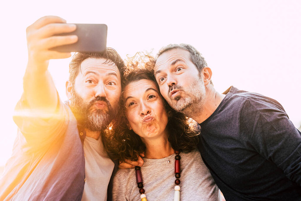 Groupe de trois jeunes amis adultes prendre des photos selfie faire belle expression - les gens d'âge moyen utilisent le téléphone portable pour prendre une photo - concept d'amitié et joyeux amis heureux - Photo, image