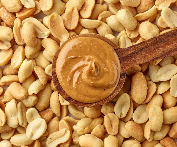 spoon of peanut butter on peanut background, top view - Photo, Image